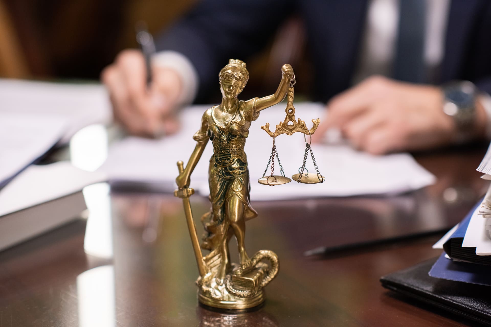 Close-up of Lady Justice statue in front of legal documents