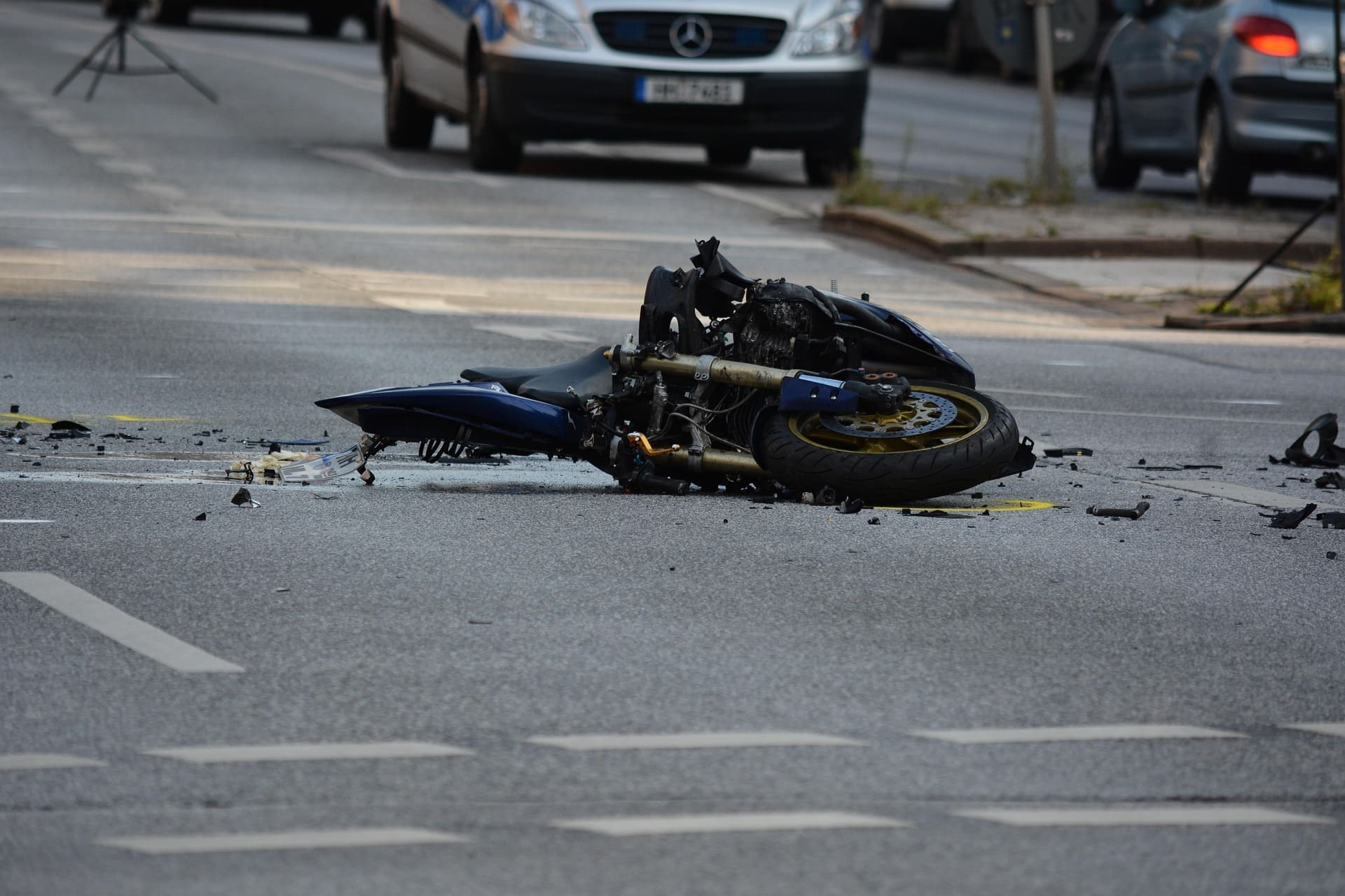 Crashed motorcycle lying in the middle of a city street with scattered debris