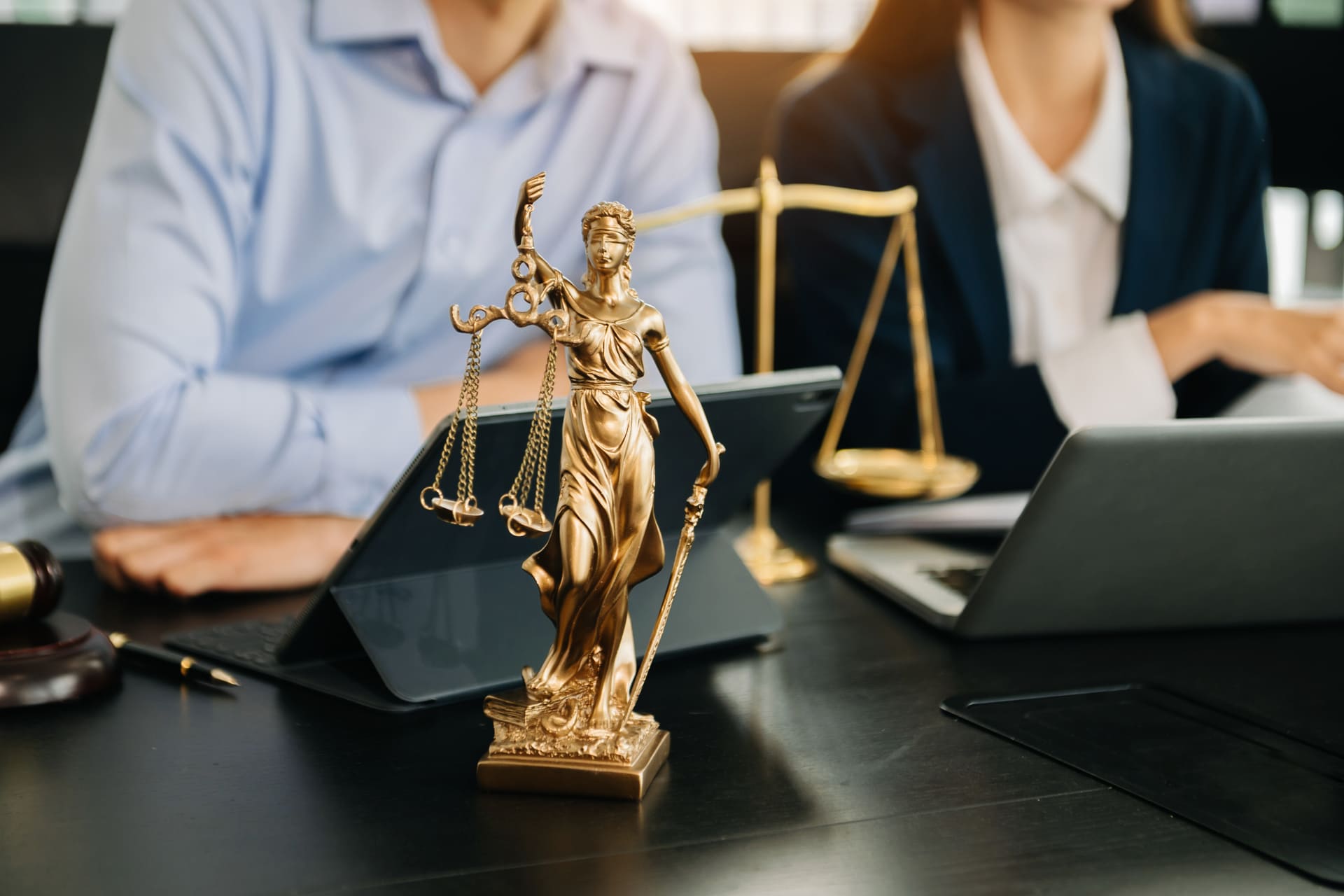 Lady Justice statue on lawyer’s desk with legal team in background